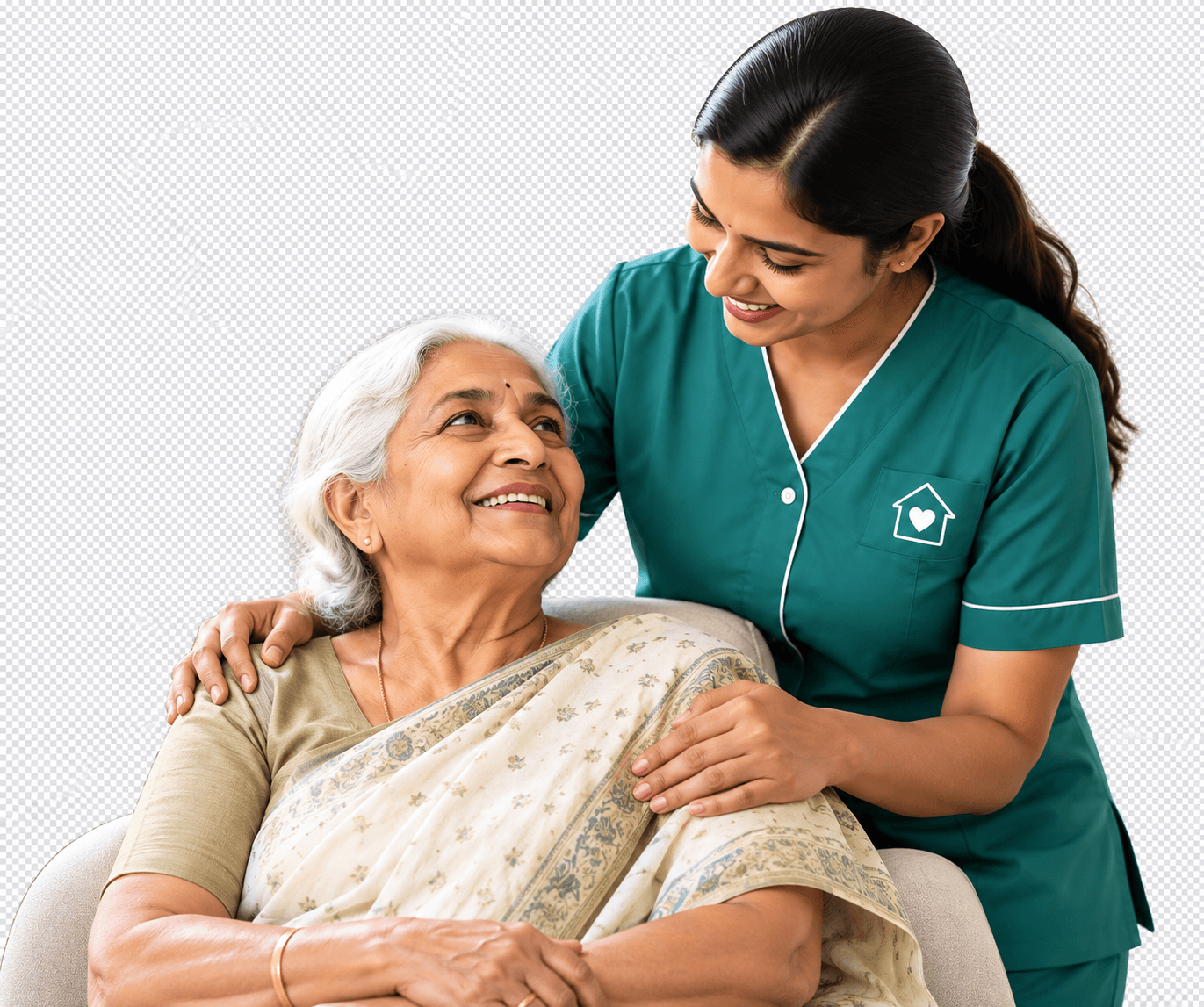 A smiling Happy Nest Home Nursing caregiver in a teal uniform standing beside a seated elderly Indian woman in a cream saree, resting a reassuring hand on her shoulder